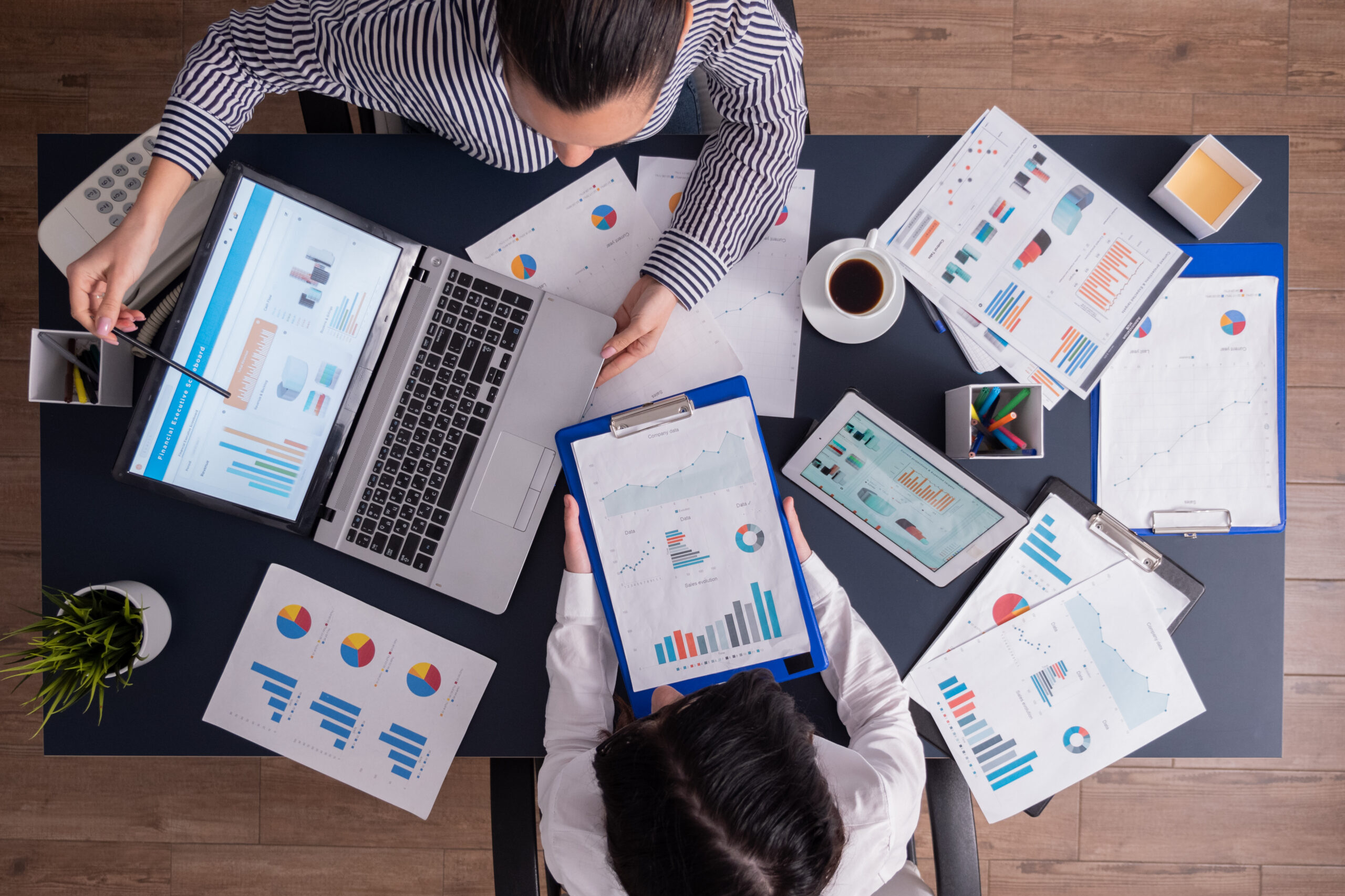 Top viewTop view of manager and employee doing teamwork in business office , looking at charts on laptop display. Finance paperwork with charts at workplace. Discusing financial plan.